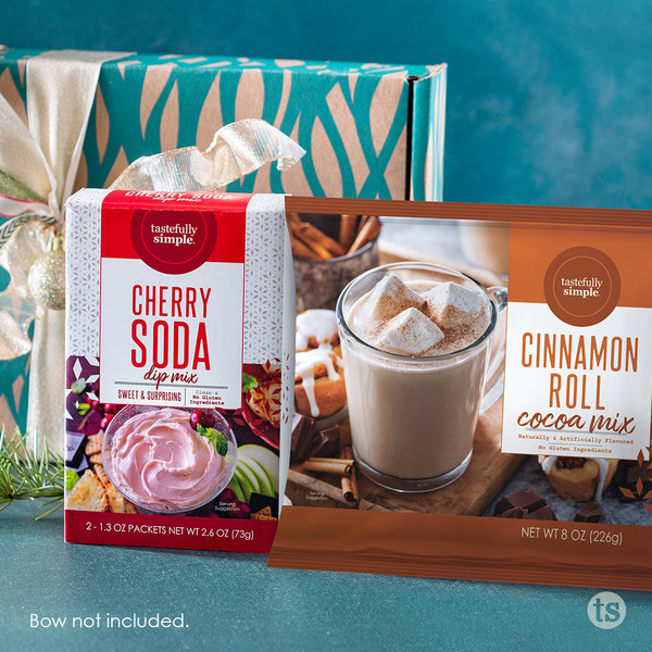 Tastefully Simple Cherry Soda Dip Mix and Cinnamon Roll Cookie Mix displayed in front of a wrapped gift box.