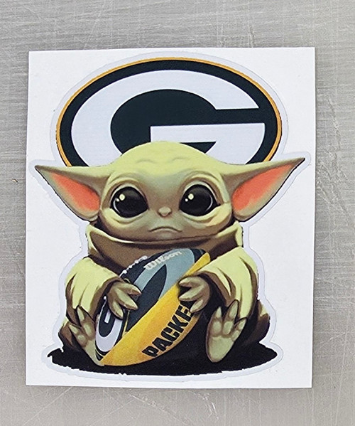 Green Bay Packers die-cut Baby Yoda vinyl decal sticker featuring Baby Yoda holding Packers gear. Durable, waterproof, UV-protected design for cars, laptops, tumblers, and more.