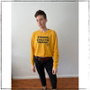 This is the front of the mustard Strong Athletic Human Long Sleeve Crop Top T-Shirt printed with black ink. We love everything about this cropped longsleeve t-shirt and we think you will too. The bottom hem of the shirt is designed to look as if you took a longer shirt and cut it shorter- so there is no stitching. 

These shirts are printed by hand by a small-scale screen printing shop. Strong Athletic is owned and run by women who are part of the LGBTQ+ community. We believe in what we do and the words that we print on our shirts. Thank you for joining our movement. 

We print this design on California based t-shirt co. StarTee. StarTee shirts are made at a W.A.R.P. Certified facility.  The Style No. for this Long Sleeve Crop Top Tee is ST 1170. 