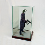 miniature Joker holding 2 guns inside glass walled figurine display box with cherry wood base