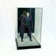 front facing figurine display box on a black base with a miniature Joker inside holding a rifle and a gun reflected in a mirror