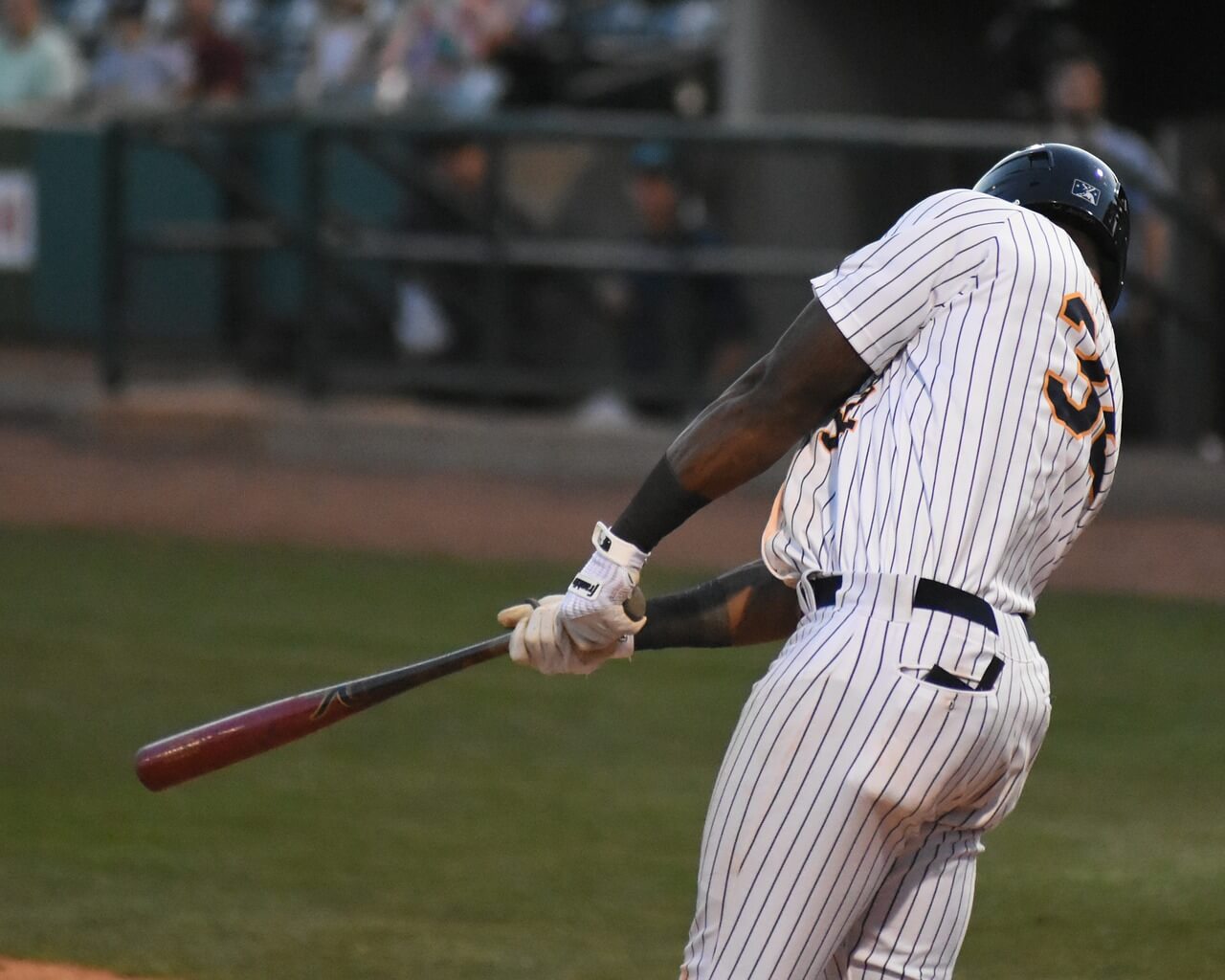 Man swinging a bat and wearing a baseball jersey