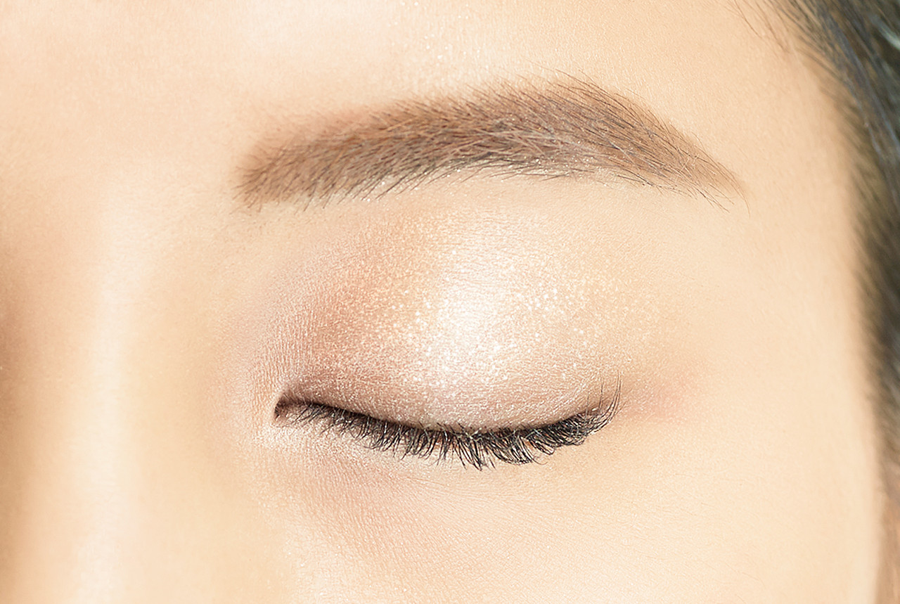 Image showing Dual Colour Stick in SV01 Marshmallow applied to the eye. There is a line of darker gold close to the lash line, with a wash of light sparkles over the rest of the lid creating a gradient effect.