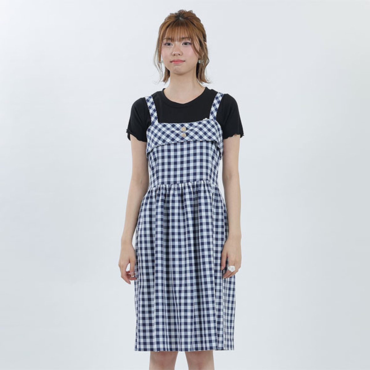 A model wearing the navy gingham sun dress. She is wearing it paired with a navy tee underneath.
