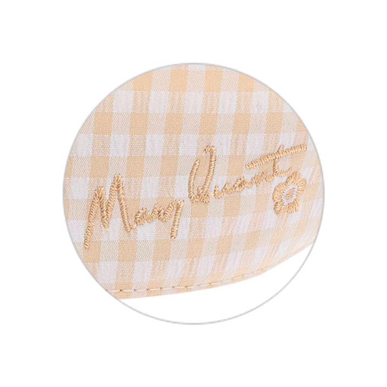 A close up of the embroidery on the beige gingham cap. Mary's signature and the Mary Quant daisy is embroidered in beige.