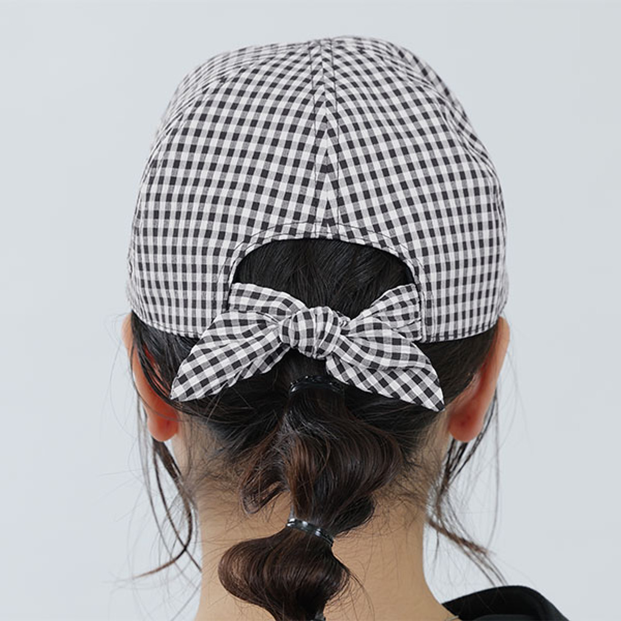 A model wears the black and white gingham cap. This photo shows the cap from the back and the cute ribbon tie detail.