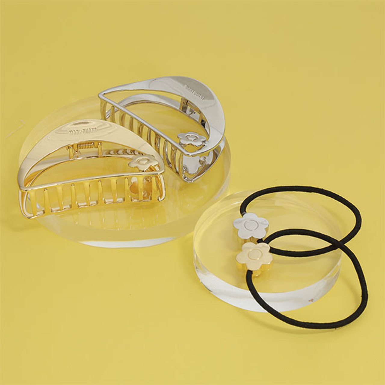 An image showing the daisy claw clips in silver and gold and the daisy hair ties in silver and gold.