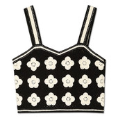 The crochet bustier in black. The bustier is black with white daisies with 4 and 5 petals scattered over it.  It is sleeveless and is made up of granny square-esque patches.