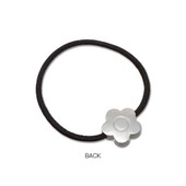 The back of the daisy hair tie in silver. A sleek metal daisy is threaded onto a simple black band.