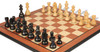 Ebonized boxwood chessmen lacquered black beside natural boxwood on mahogany board
