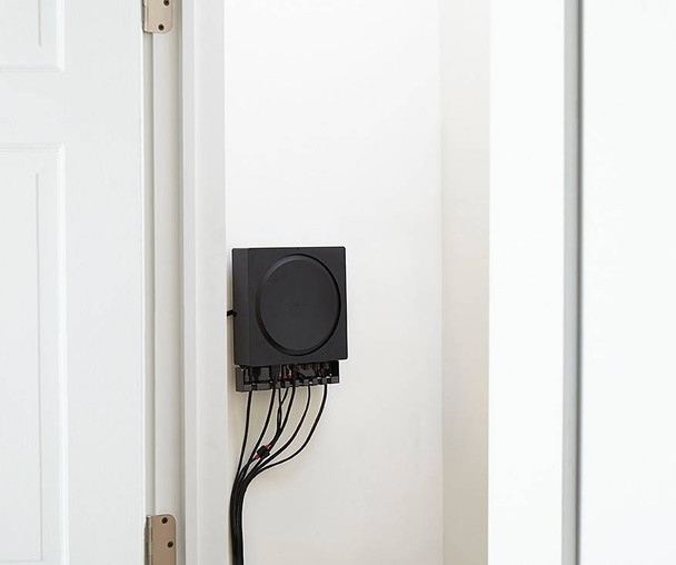 Sanus WSSCAM1 mounted on wall with cable clips organizing cords around Sonos Amp ports
