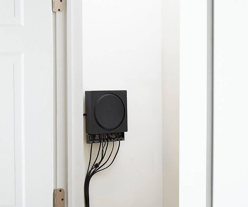 Sanus WSSCAM1 mounted on wall with cable clips organizing cords around Sonos Amp ports
