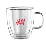 A drink cup made of transparent glass with a red logo, featuring a double wall design and comfortable handle.