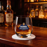 A stemless glass cup filled with amber liquid, featuring a logo, sitting on a bar counter.