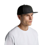 A faded black trucker cap with a structured front and mesh back, worn by a model in a white shirt.
