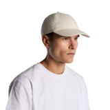 A light-coloured cap worn by a male model, featuring a simple design and a logo.