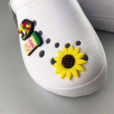 Jibbits Shoe Charms in vibrant colours, featuring a sunflower and playful designs, positioned on a white shoe.
