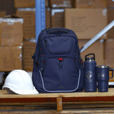A navy travel backpack with a front pocket, a white hard hat, and two drink bottles, one insulated and one tumbler.