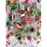 Individually wrapped rock candy in various colours, including pink, green, blue, and red, arranged in a large pile.