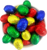 A bowl filled with small, colourful chocolate eggs wrapped in shiny foil—red, green, blue, and gold.