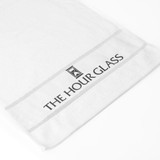 A white cotton gym towel featuring a logo along the edge and a textured design.