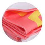 A folded sublimated beach towel in pink and yellow with a logo, showcasing a soft, vibrant design.