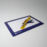A blue deluxe counter mat features a ruler, scissors, and a pen on a white surface. It has a logo in one corner.