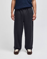 Open-bottom fleece pants in black, featuring pockets and an elastic waistband, worn by a person standing.