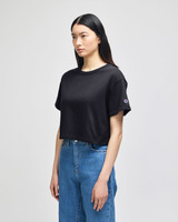A cropped black t-shirt with short sleeves and a logo detail, styled with blue denim jeans.