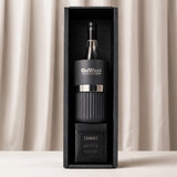 A black wine bottle cooler, a glass tumbler, and a box of brittle, all packaged in a stylish gift box.