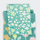 Knitted bamboo kids socks in teal with floral patterns, featuring a colourful card with a flower design.