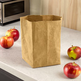 A kraft paper storage bag in a natural brown colour, surrounded by red apples on a kitchen countertop.