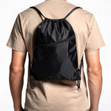 A black drawstring bag is worn on a person's back, featuring a front pocket and adjustable straps.