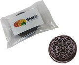 A packed OREO biscuit in a clear wrapper with a branded label. The biscuit is dark brown.