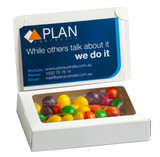 A boxed selection of multicoloured Skittles in a clear window, featuring a branding logo on the front.
