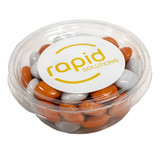 A clear tub filled with orange and grey choc beans, featuring a logo on the lid.
