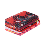 A stack of colourful sublimated beach towels featuring various vibrant patterns, including reds, pinks, and blacks.