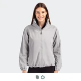 A full zip women's jacket in light grey, featuring a high collar and elasticated hem. It has a logo on the chest.
