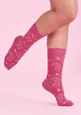 Unisex pink socks featuring a playful heart and flower design, displayed on a foot against a pink background.