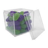 A clear cube container filled with green and purple jelly beans, partially open.