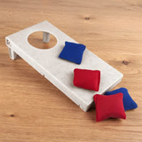 A cornhole board made of wheat straw in a light colour, accompanied by four small, red and blue bean bags.