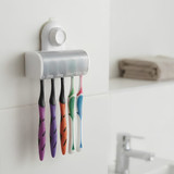 A white toothbrush holder mounted on a wall, featuring five toothbrushes in purple, orange, green, and blue.