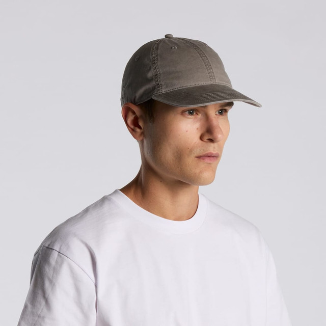 A faded grey cap with a curved brim, worn by a person in a plain white t-shirt. Features branding on the side.