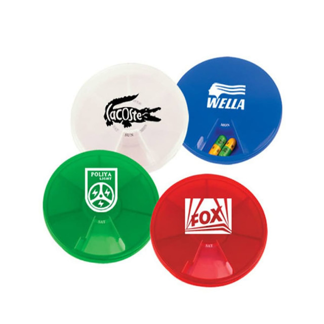 A set of four circular pill boxes in green, red, blue, and clear, each featuring a logo and multiple compartments.