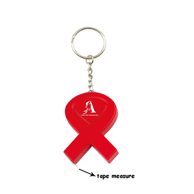 A red key tag in the shape of a ribbon featuring a tape measure attachment and a logo.