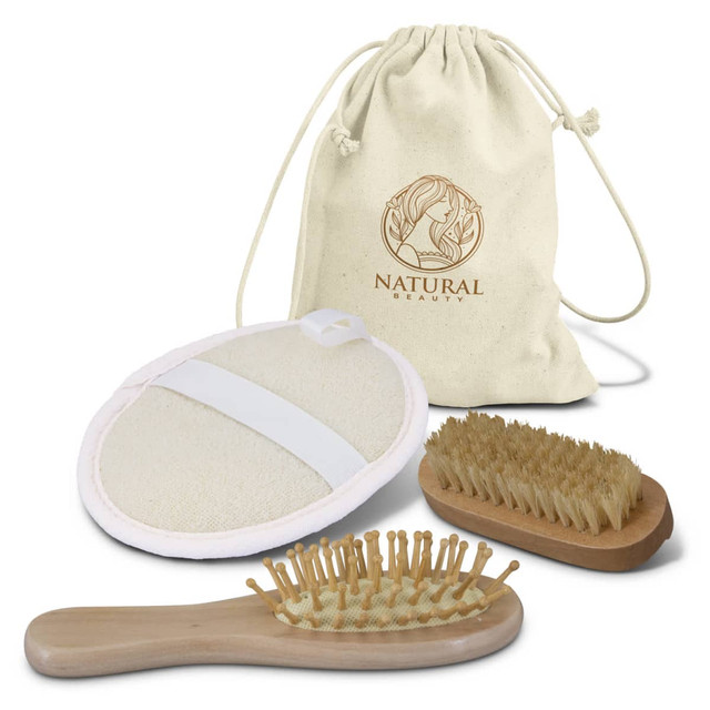 A natural beauty travel set featuring a cream drawstring bag, a massage brush, and a facial exfoliating pad in beige.