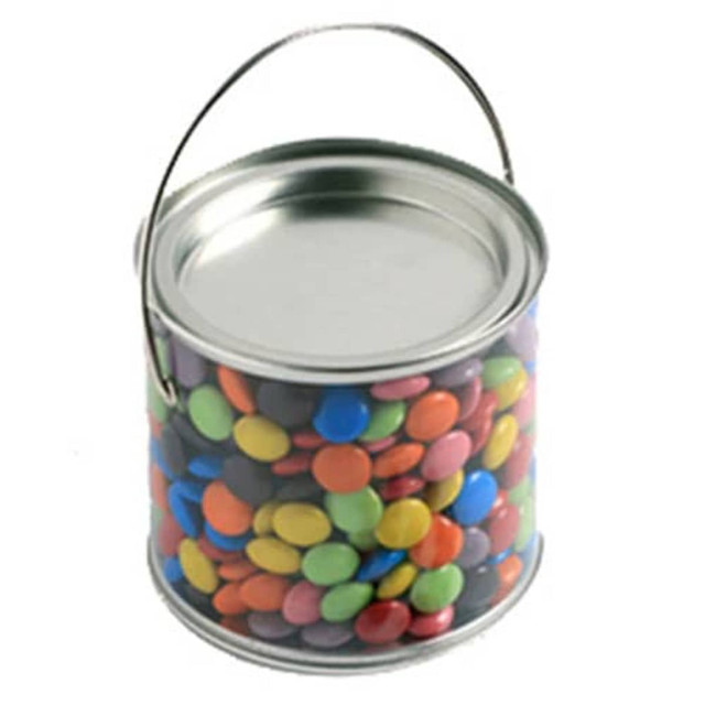 A medium, clear PVC bucket filled with colourful choc beans, featuring a metallic handle.