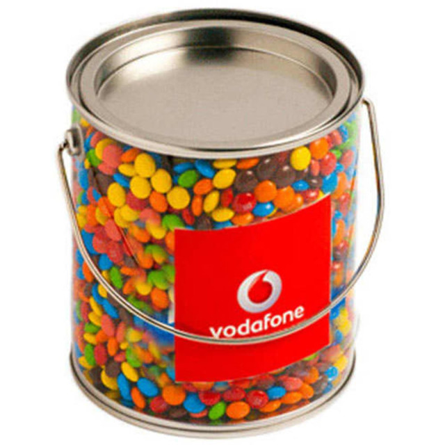 A big PVC bucket filled with colourful M&Ms, featuring a silver handle and a branded label.