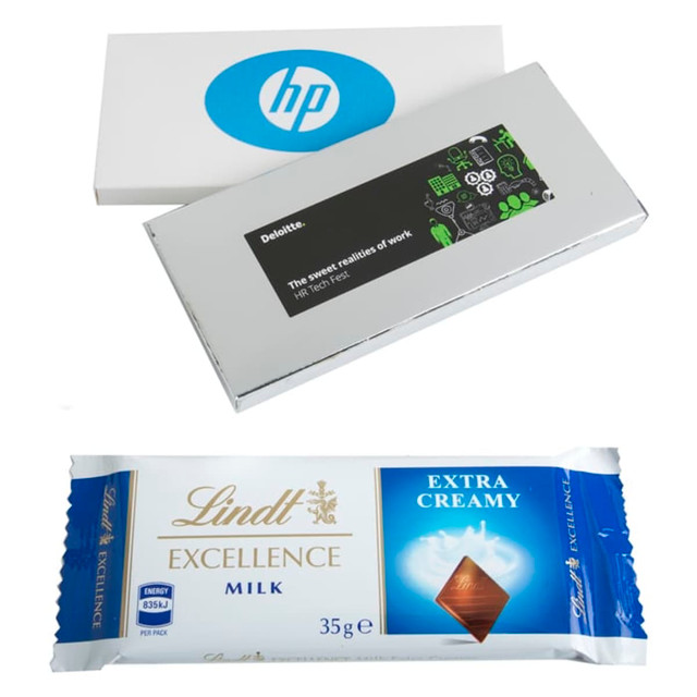 A silver box containing a 35g Lindt chocolate bar, labelled as Extra Creamy Milk, alongside a white box with a logo.