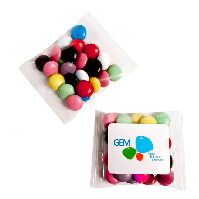 A bag of colourful chocolate beans in various shades, including pink, blue, yellow, and red, with a logo on the packaging.